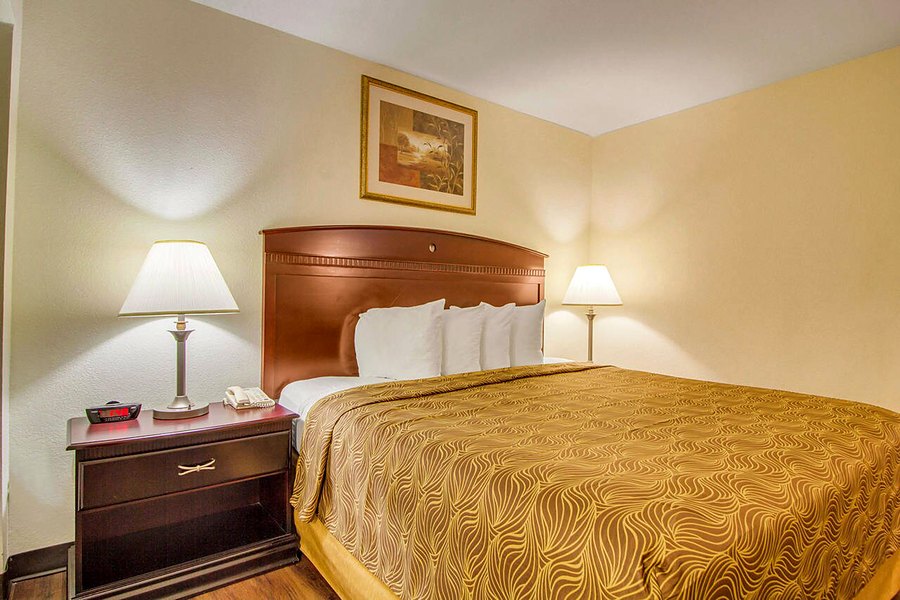 King bed suite with a wooden headboard, two bedside lamps and a framed print.