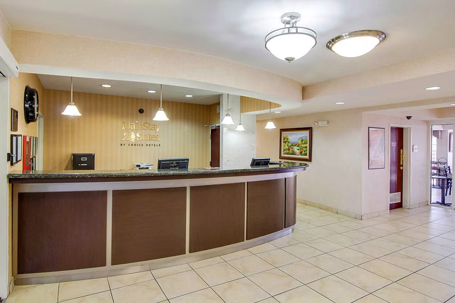Hotel lobby with a curved wooden front desk and pendant lighting.