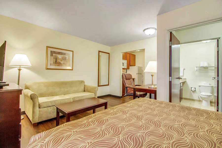 Queen suite with a sofa, side table, lamp and an open doorway to the bathroom.